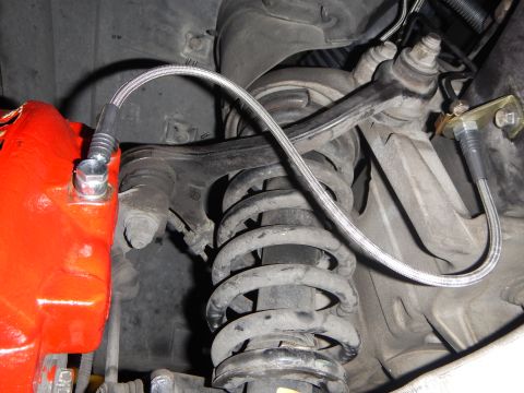 2003 Ford Crown Victoria - Photo of front suspension components including coil spring, control arm and braided brake line.