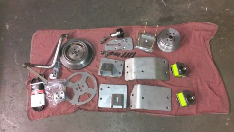1996 Ford Bronco - A collection of automotive parts, including a brake rotor, belts, brackets, pulleys, and engine mounts, are laid out on a red cloth on a co…
