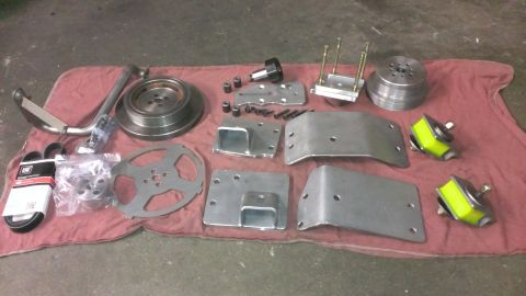 1996 Ford Bronco - A collection of engine parts, including pulleys, belts, brackets, and motor mounts, are laid out on a red cloth.