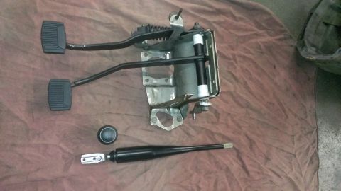 1996 Ford Bronco - A clutch pedal assembly, a brake pedal, a shift knob, and a shifter lever are laid out on a brown cloth surface.
