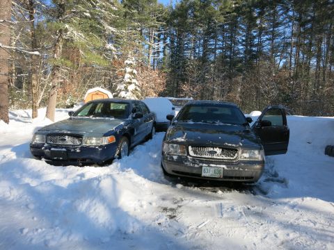 2001 Ford Crown Victoria - Photograph of former police sedans in snow, not a technical document.