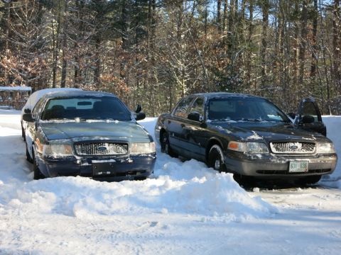 2001 Ford Crown Victoria - Photograph of former police sedans in snow, not a technical document.