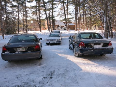 2001 Ford Crown Victoria - Photograph of former police sedans in snow, not a technical document.