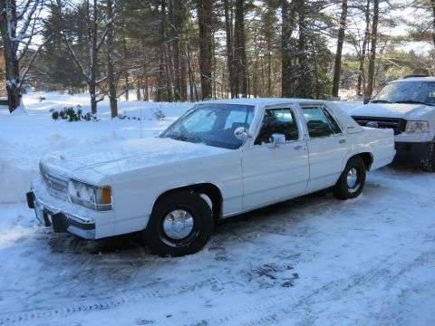 2001 Ford Crown Victoria - Photograph of a white Ford LTD Crown Victoria sedan parked in snow among trees, not a technical document.