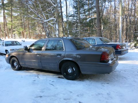 2001 Ford Crown Victoria - Photograph of a gray Ford Crown Victoria sedan with black steel wheels in snow, not a technical document.