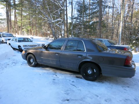 2001 Ford Crown Victoria - Photograph of a gray Ford Crown Victoria sedan in a snowy lot with other cars, not a technical document.