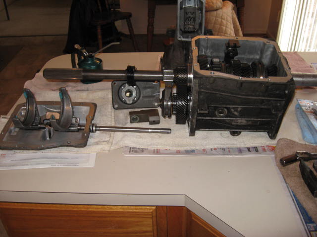 Disassembled manual transmission with gears and shafts on a table.