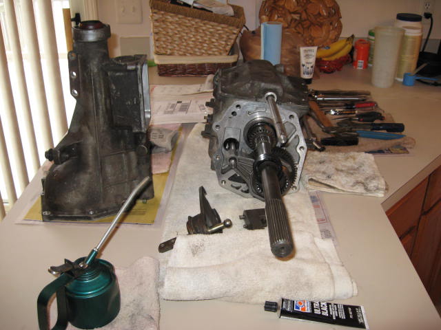 Disassembled manual transmission with tools and oil can on a countertop.