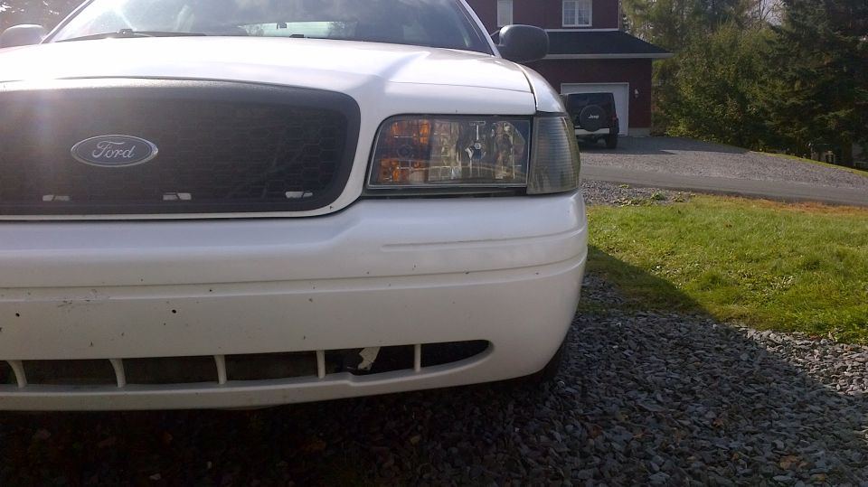White Ford Crown Victoria front end with black grille and headlights.