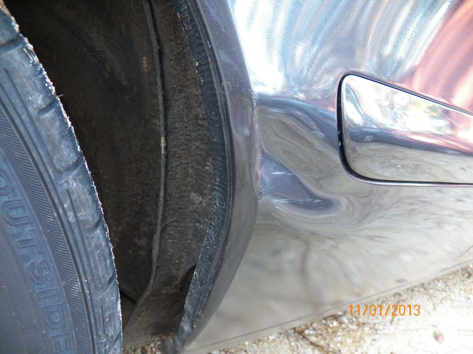 Close-up of a car's wheel well, tire, and body panel with a fuel door.