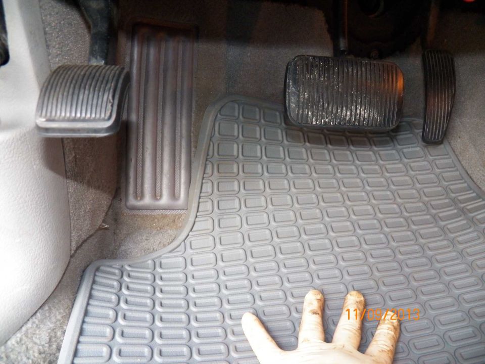 Driver's side pedals and floor mat in a vehicle.