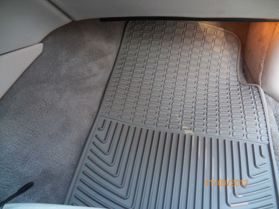 Gray rubber floor mat with patterned and ribbed texture inside a vehicle.