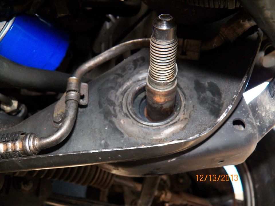 Close-up of vehicle suspension with threaded shaft and blue oil filter.