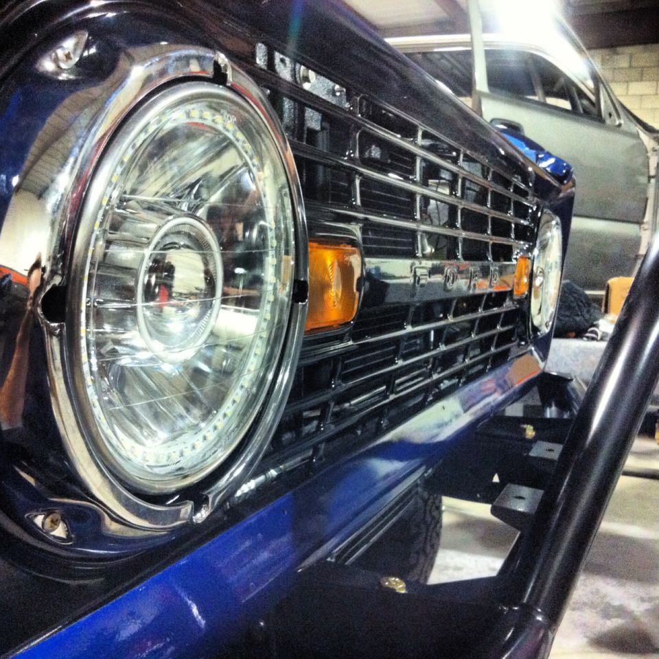 Close-up of a dark blue Ford Bronco front grille and LED halo headlight.