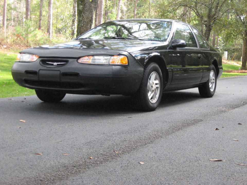 Black 1997 Ford Thunderbird coupe with a car bra parked on an asphalt driveway.