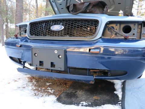 2001 Ford Crown Victoria - Photograph of a blue Ford Crown Victoria front with detached bumper cover, not a technical document.