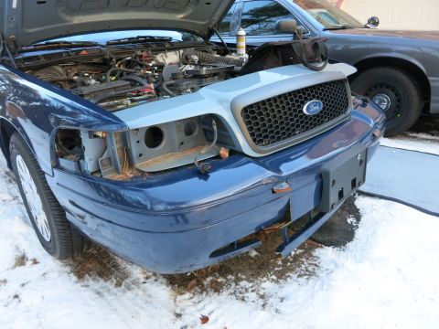 2001 Ford Crown Victoria - Photograph of a blue Ford Crown Victoria with hood up and bumper cover removed, not a technical document.