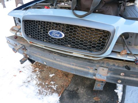 2001 Ford Crown Victoria - Photograph of a Ford grille and exposed front bumper bar during repair, not a technical document.