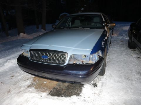 2001 Ford Crown Victoria - Nighttime photograph of a two-tone Ford Crown Victoria front end during bumper work, not a technical document.