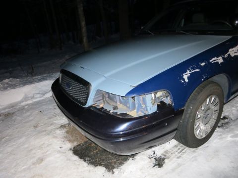 2001 Ford Crown Victoria - Nighttime close-up photograph of a Ford Crown Victoria front corner with bumper detached, not a technical document.