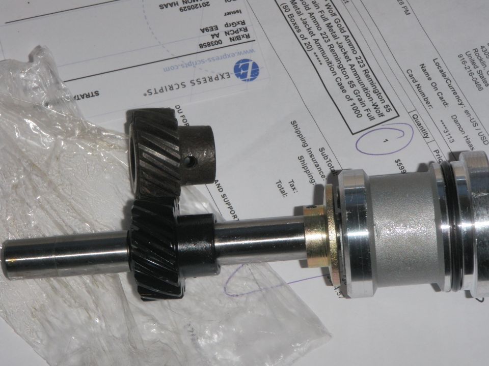 Two metal gears on a shaft on top of a shipping document.