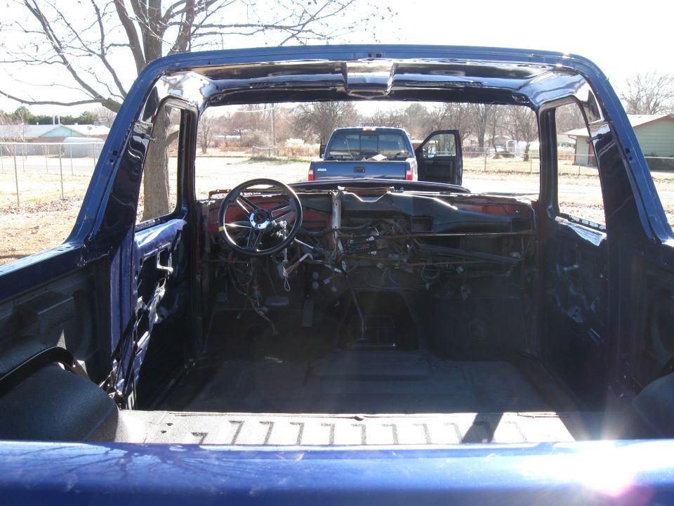 Interior of a blue Ford Bronco with doors removed, showing dashboard and steering wheel.