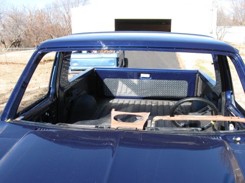 1982 Ford Bronco - The interior of a dark blue pickup truck is shown from a front-facing angle, with the windshield removed. A steering wheel and part of the…