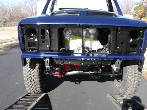 1982 Ford Bronco - The front of a blue 1982 Ford Bronco is shown with the hood open, revealing the engine bay which is covered in protective wrapping. The veh…