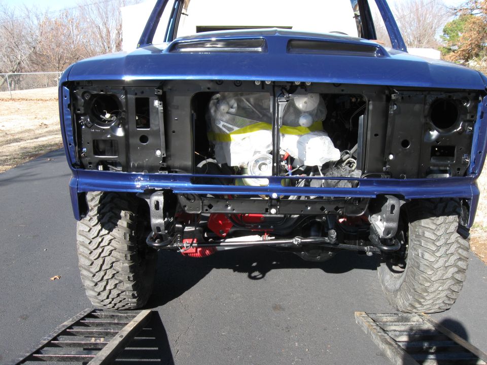 Blue 1982 Ford Bronco front view, engine bay exposed, on a ramp.
