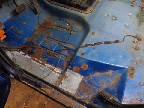 1979 Ford Bronco - The interior floor of this vehicle shows extensive rust damage and exposed wiring, indicating a need for restoration.