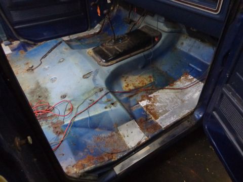 1979 Ford Bronco - The interior of this vehicle shows significant rust on the floorboards and exposed wiring, indicating a need for restoration.