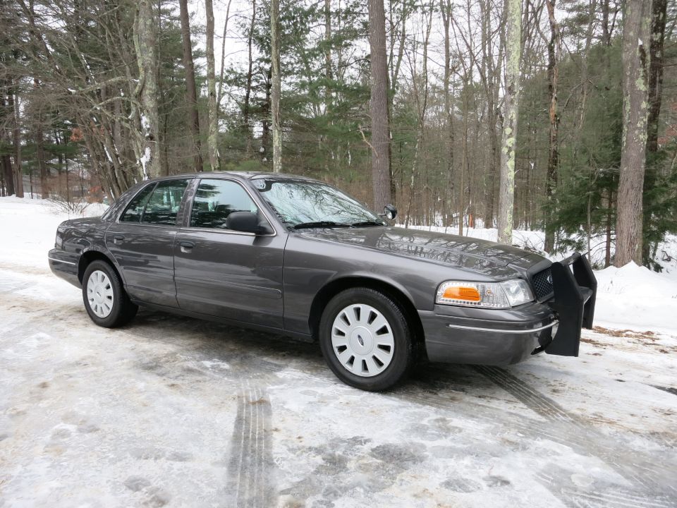 Gray Ford Crown Victoria with push bar parked in a snowy driveway