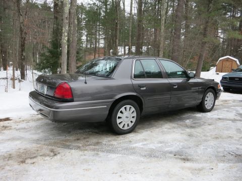 2001 Ford Crown Victoria - Photograph of a gray Ford Crown Victoria sedan rear-quarter view in snow, not a technical document.