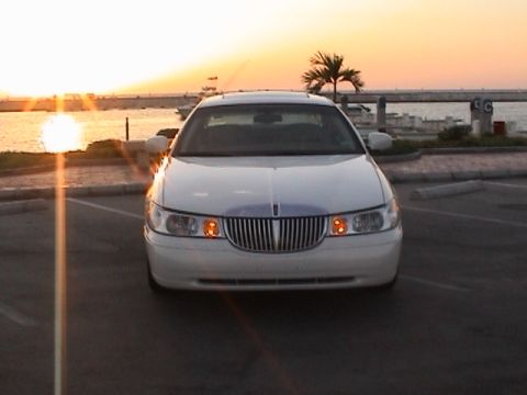 2002 Lincoln Town Car - A white 2002 Lincoln Town Car is parked near the water with a sunset in the background.