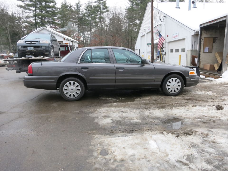 Passenger-side profile of gray Ford Crown Victoria in front of a garage