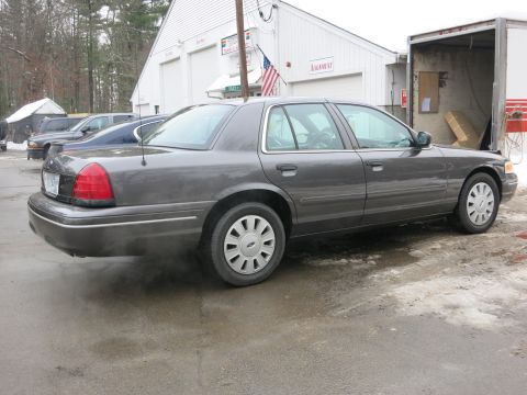 2001 Ford Crown Victoria - Photograph of a Ford Crown Victoria from the rear quarter near a garage, not a technical document.