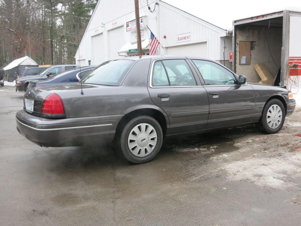 Rear three-quarter view of gray Ford Crown Victoria with exhaust vapor