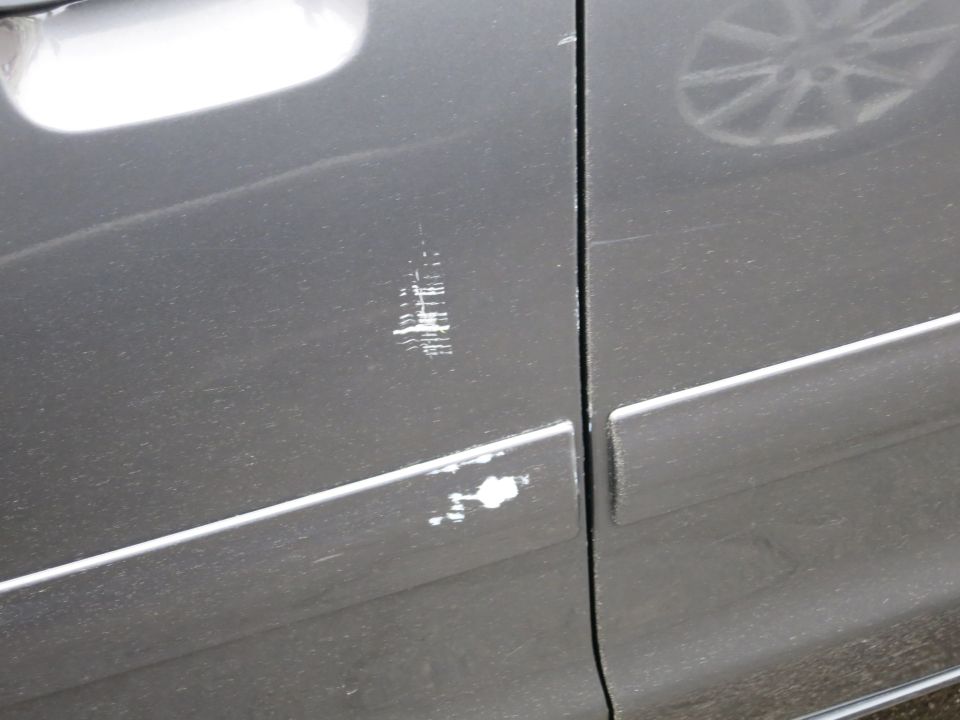 Close-up of scratches and paint damage on gray car door panel