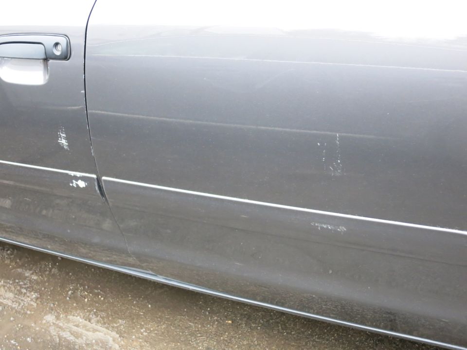 Close-up of door and rocker panel on gray vehicle showing minor scuffs