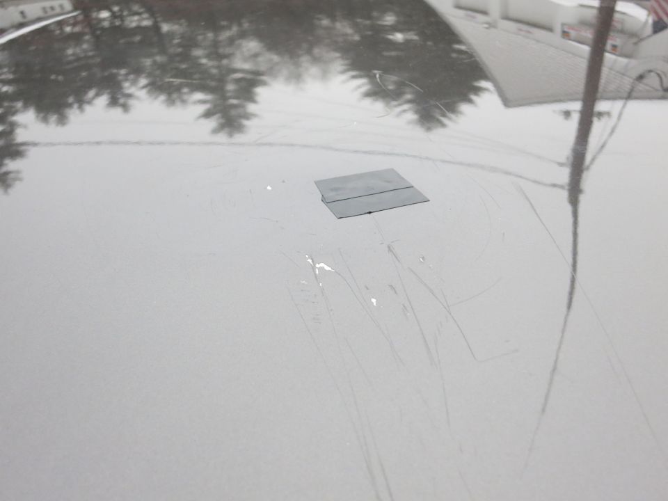 Close-up of gray hood with scratches and a small applied patch