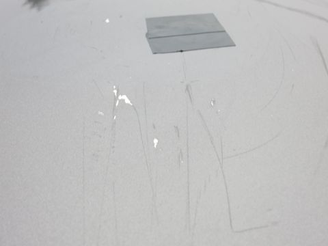 2001 Ford Crown Victoria - Close-up photograph of a scratched vehicle hood with a patch, not a technical document.