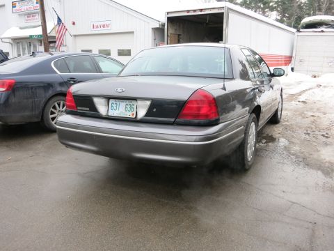 2001 Ford Crown Victoria - Photograph of a Ford Crown Victoria from the rear quarter near a shop, not a technical document.
