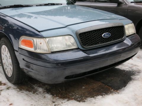 2001 Ford Crown Victoria - Close-up photograph of the front corner of a blue Ford Crown Victoria, not a technical document.