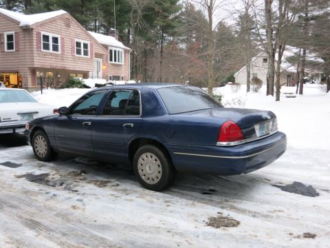 2001 Ford Crown Victoria - Photograph of a blue Ford Crown Victoria sedan in a snow-covered residential driveway, not a technical document.