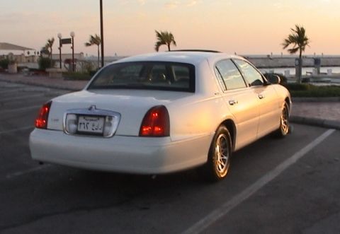 2002 Lincoln Town Car - Rear view of a white 2002 Lincoln Town Car parked near the water at sunset.