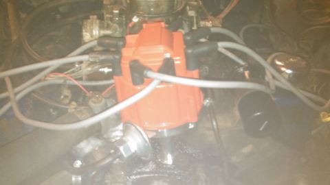 1979 Ford Bronco - A close-up view of an orange HEI distributor cap with spark plug wires connected in an engine bay. The distributor is mounted on a chrome s…