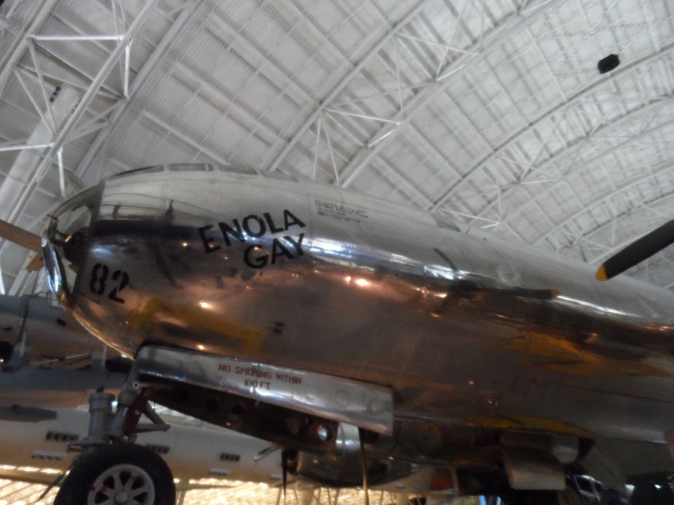 Enola Gay nose art on a silver B-29 Superfortress airplane indoors.