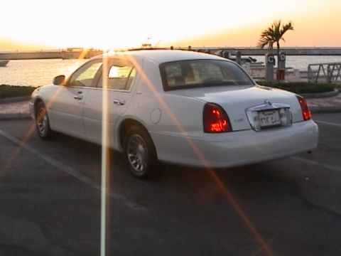 2002 Lincoln Town Car - A white 2002 Lincoln Town Car is parked by the water as the sun sets.