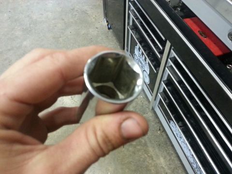 1995 Ford F-150 - A close-up view of a socket wrench held in a hand, with a toolbox in the background.