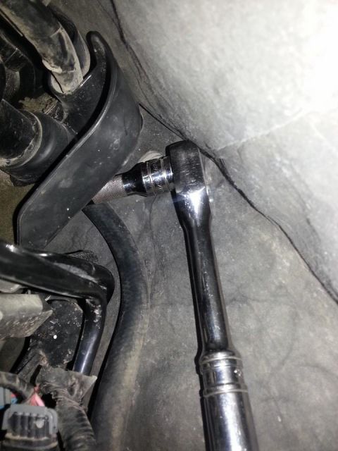 1995 Ford F-150 - A socket wrench is used to tighten a bolt in a tight space with hoses and textured surfaces visible.